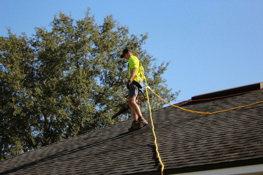 Roof worker in hi-vis and a safety harness walking a pitched roof on a tethered rope line